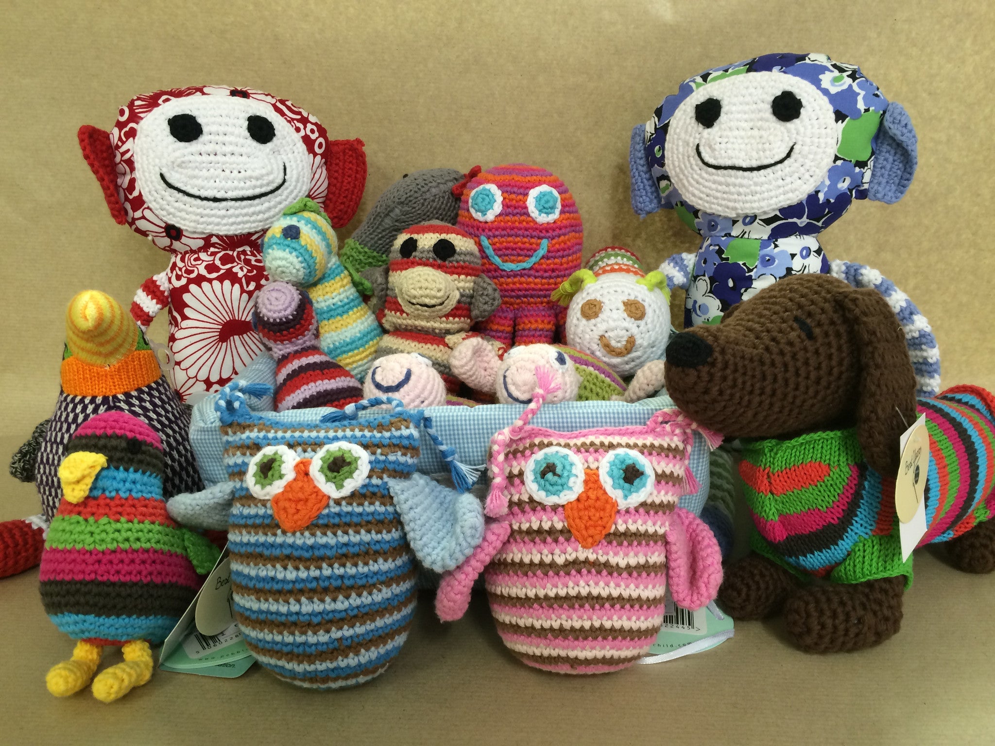 A collection of brightly coloured knitted and crochet soft toys displayed on a brown paper background.