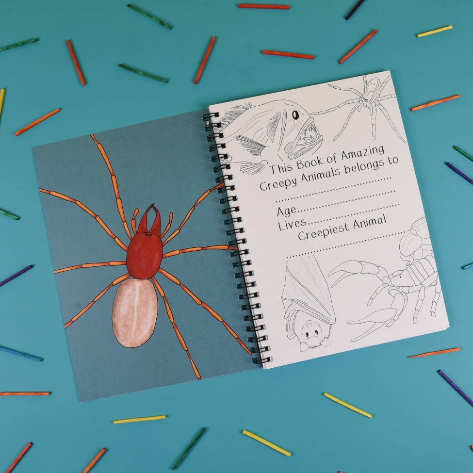 Coloring book with spider illustration on a blue background with colored pencils.