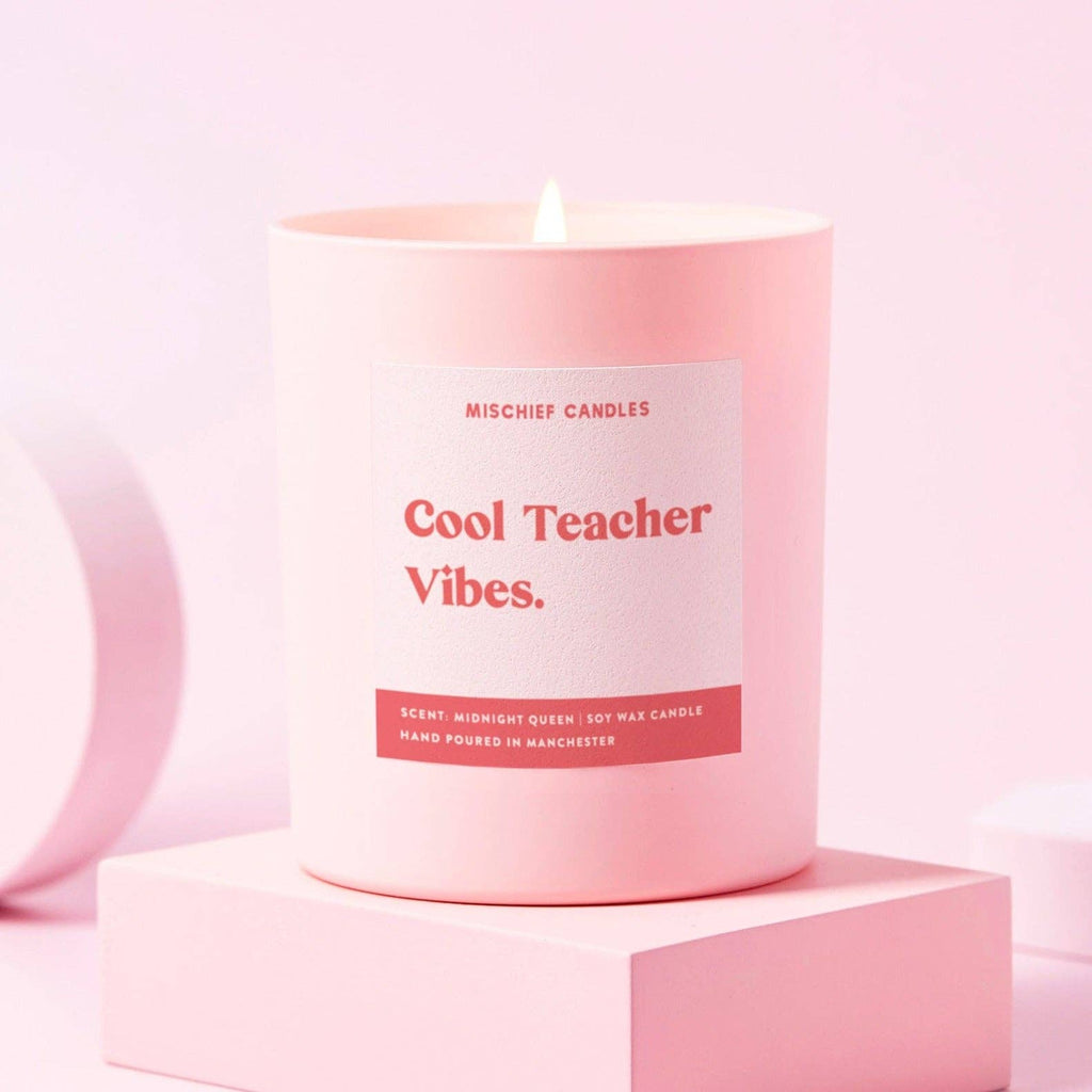 Pink glass jar candle with 'cool teacher vibes' label.