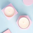 Two white candles in pink holders on a light blue background