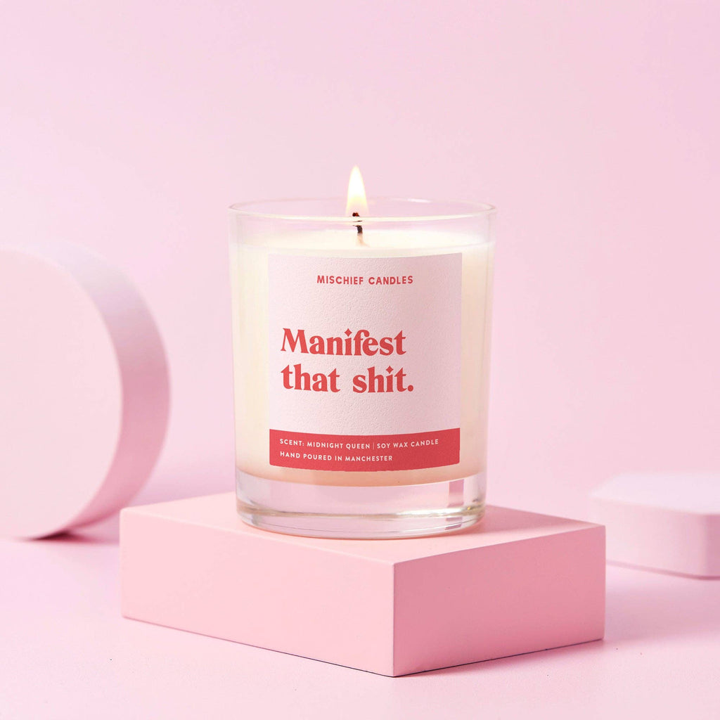 Candle with a humorous label on a pink surface
