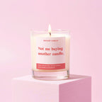 Candle with a humorous label ' not me buying another candle' on a pink background