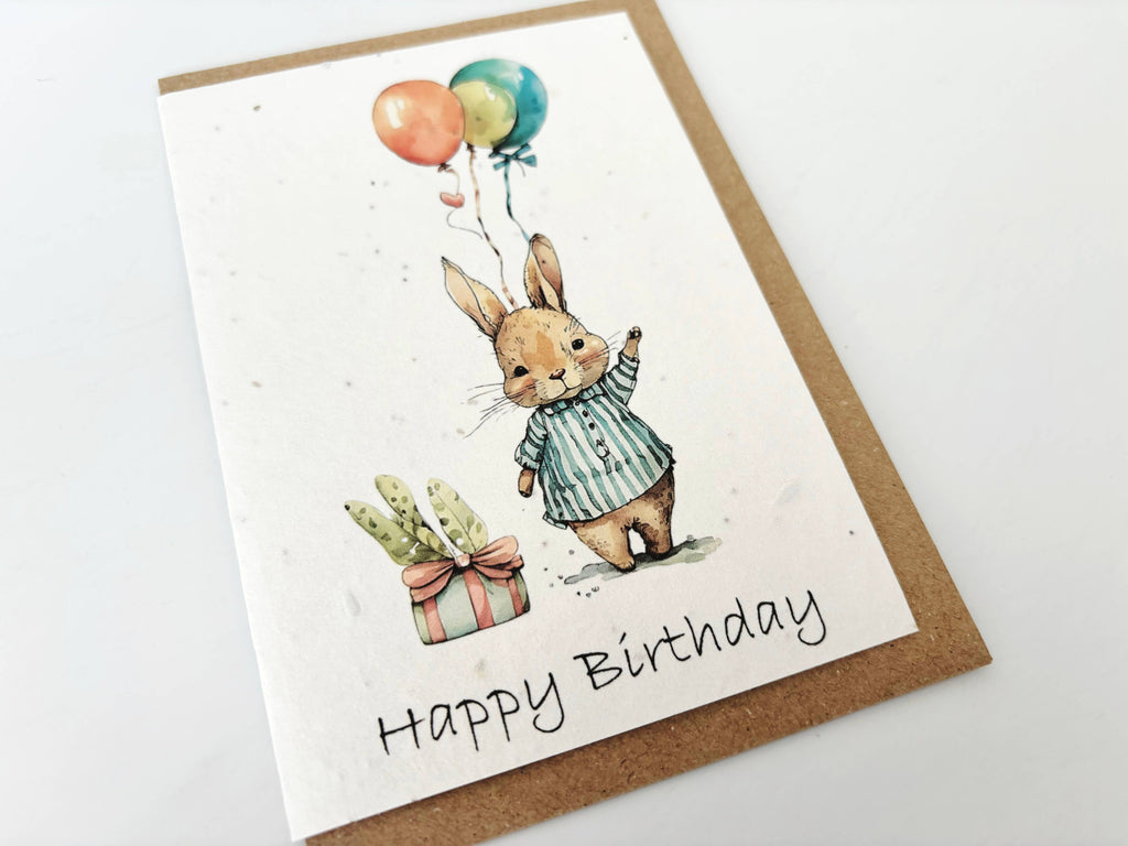 Birthday card with a rabbit holding balloons and the text 'Happy Birthday' on a white background.