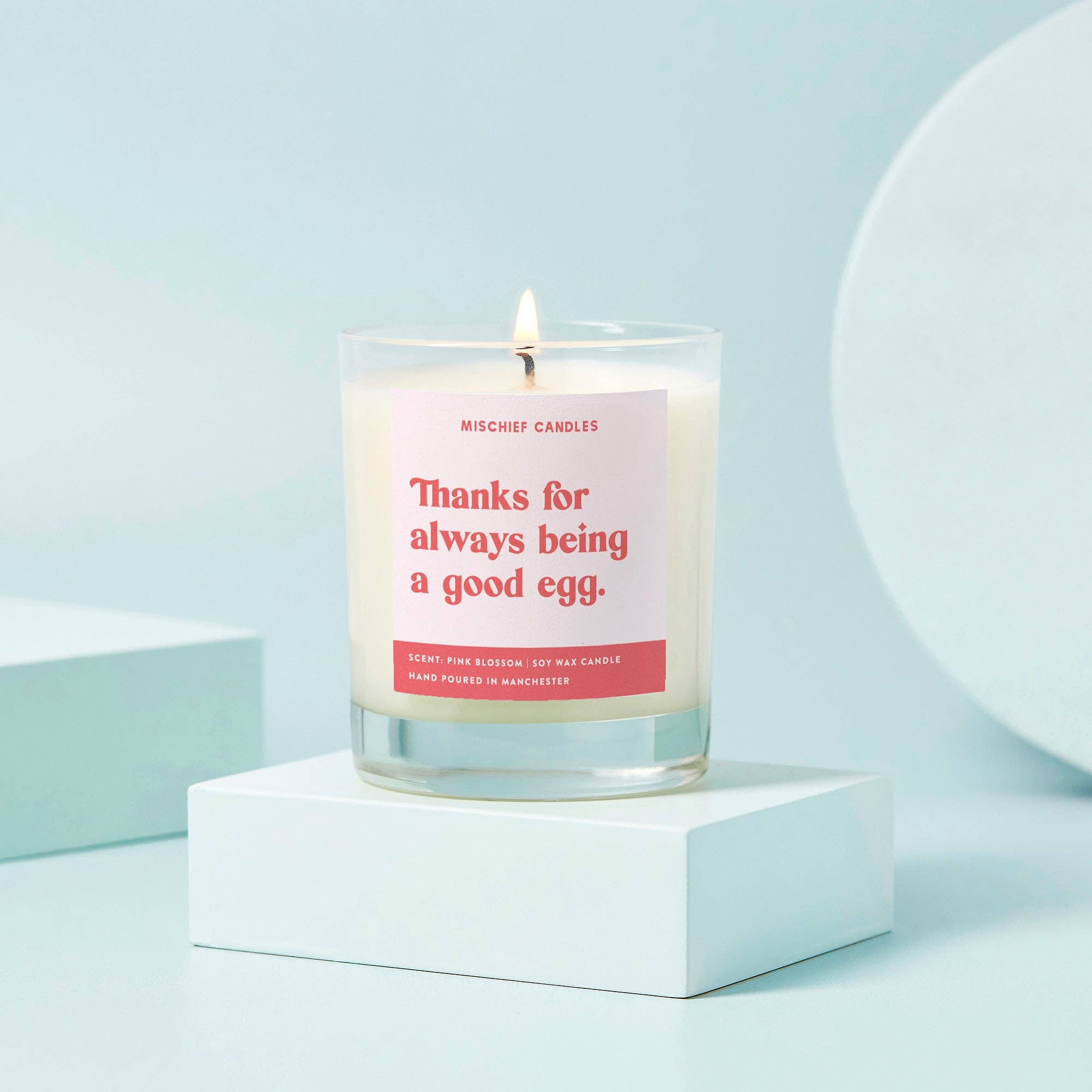 Candle with a pink label on a light blue background