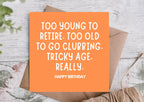 Orange birthday card with humorous text on a wooden surface