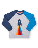 Grey jumper with a rocket on the front, sleeves are two different blues.